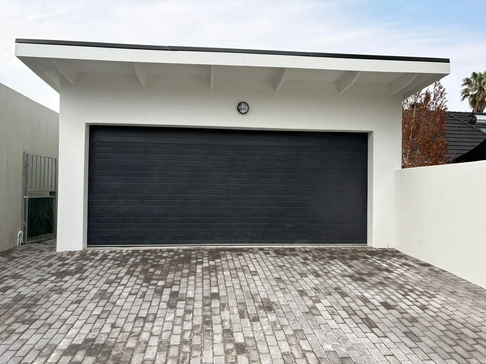 Garage with black door and paved driveway
