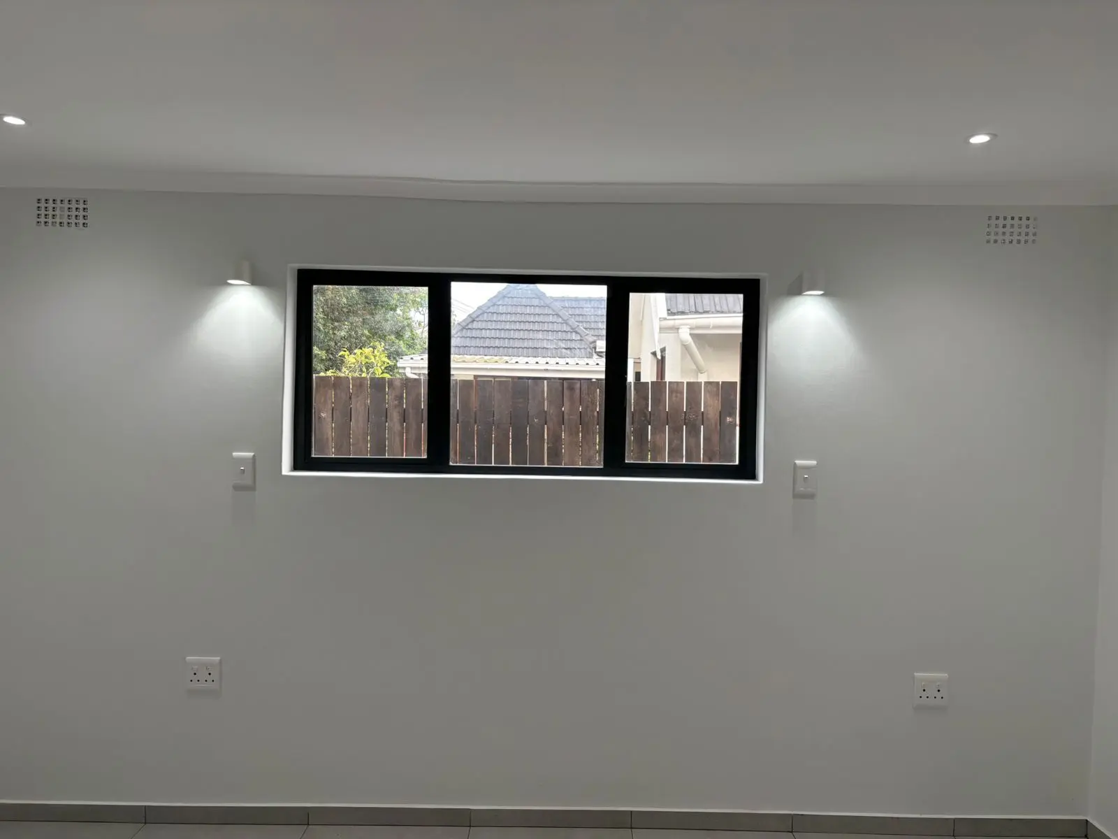 Black-framed window with lighting and wall finishes